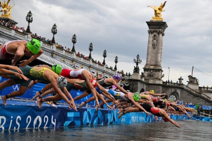 Triathletes dive into the River Seine at the start of the Olympic triathlon