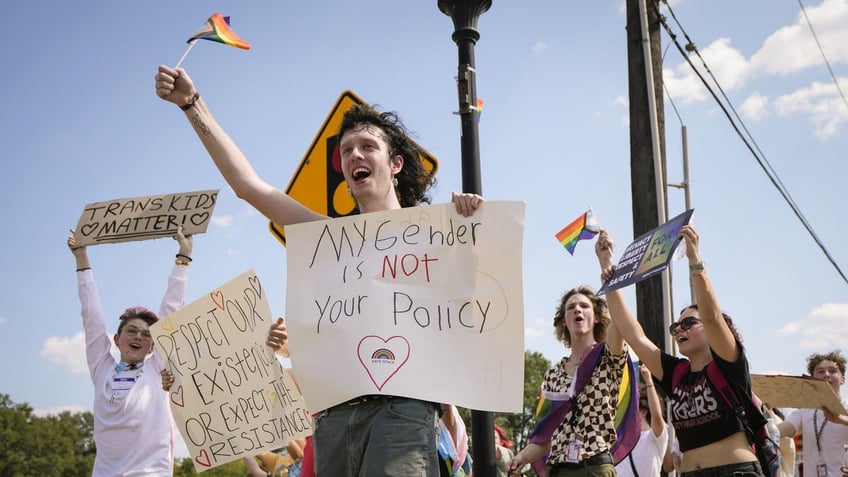 Trans rights protester holds sign