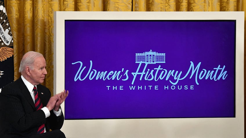 Joe Biden standing by Women's History Month sign