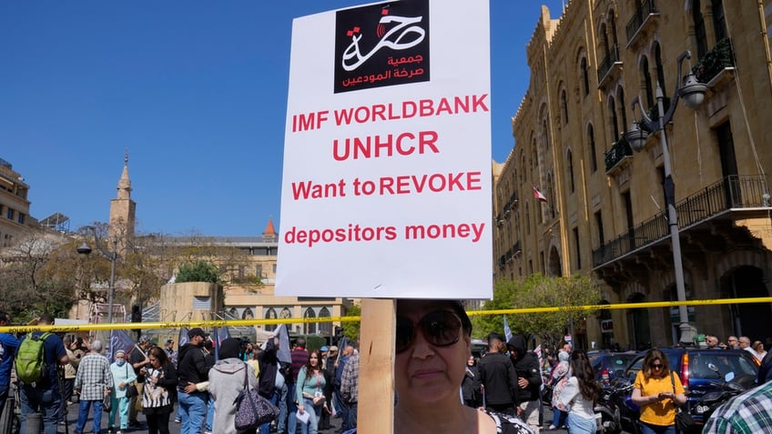 A protesting depositor carries a placard at a protest near Parliament in downtown Beirut, Lebanon