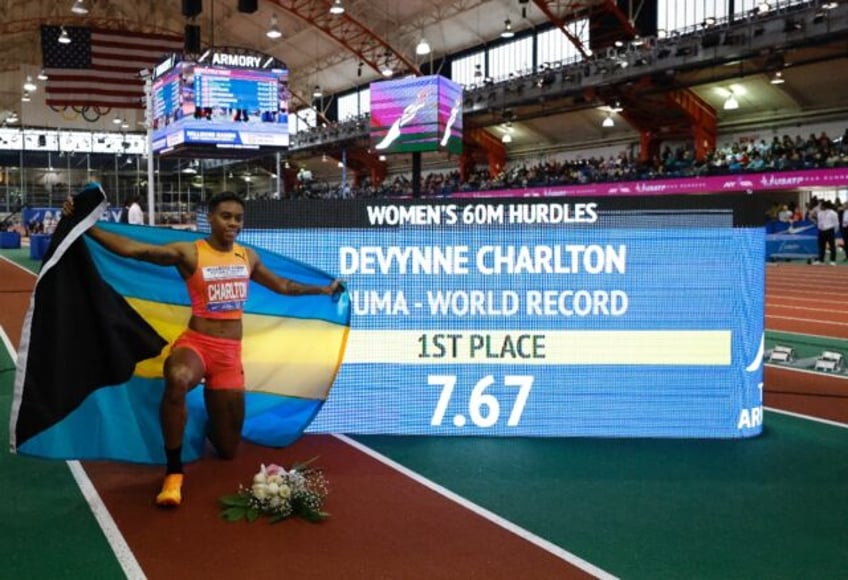 Devynne Charlton of the Bahamas poses in front of the scoreboard after setting a world ind