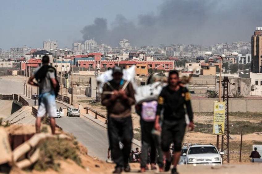 People flee as smoke rises above buildings near the Al-Shifa hospital compound during Isra