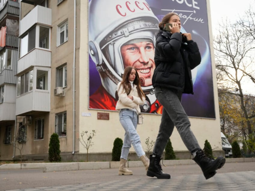 People walk past a billboard depicting the first cosmonaut Yuri Gagarin in Tiraspol, the c