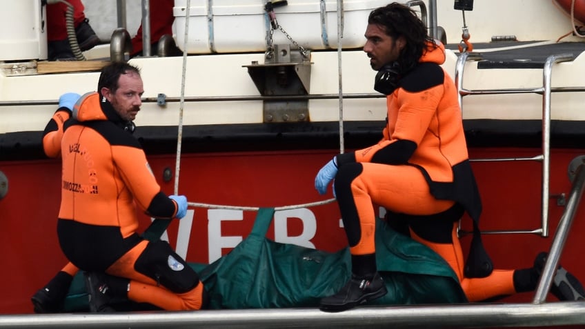 Italian firefighter scuba divers bring ashore, in the green bag, the body of one of the victims from the British-flagged vessel Bayesian, Wednesday, Aug. 21, 2024. The yacht was hit by a violent sudden storm and sank early Monday, while at anchor off the Sicilian village of Porticello near Palermo, in southern Italy.