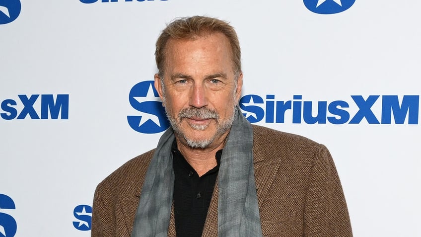 Kevin Costner posing in front of SiriusXM signage