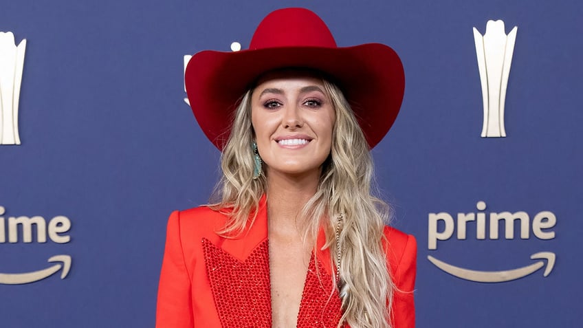 Lainey Wilson in a red suit and hat at the CMA Awards