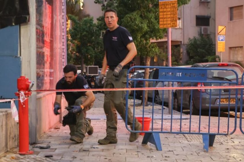 Israeli security personnel inspect the area around the Tel Aviv apartment building where t