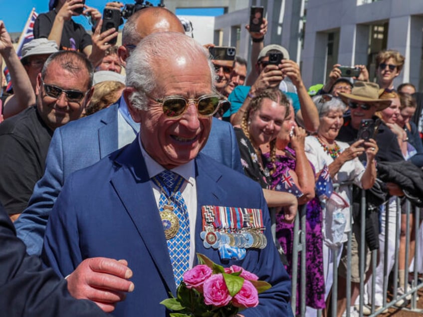 Britain's King Charles III receives a bouquet of roses as he meets members of the pub