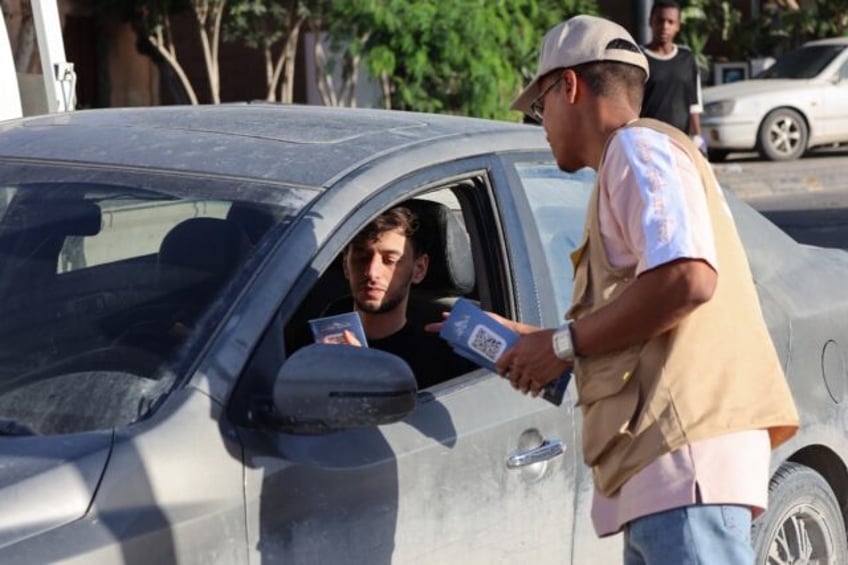 A campaigner hands an election leaflet to a driver ahead of the vote in Misrata