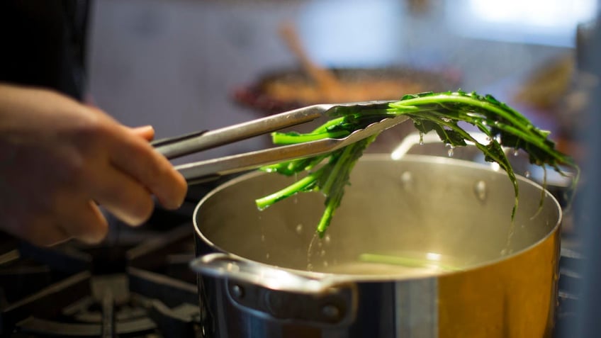 A person removing cabbage from a pot