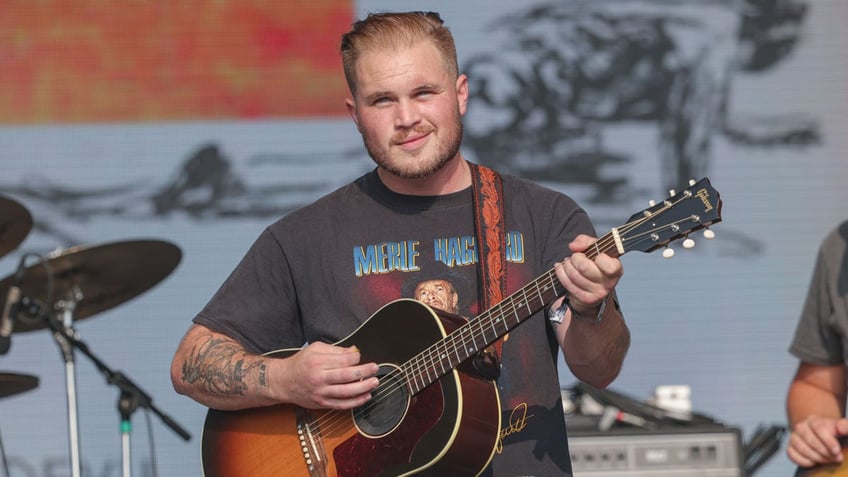 Zach Bryan plays guitar on stage