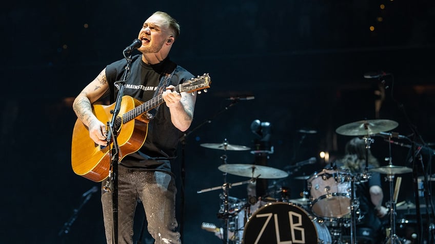 Zach Bryan performs on stage with a guitar