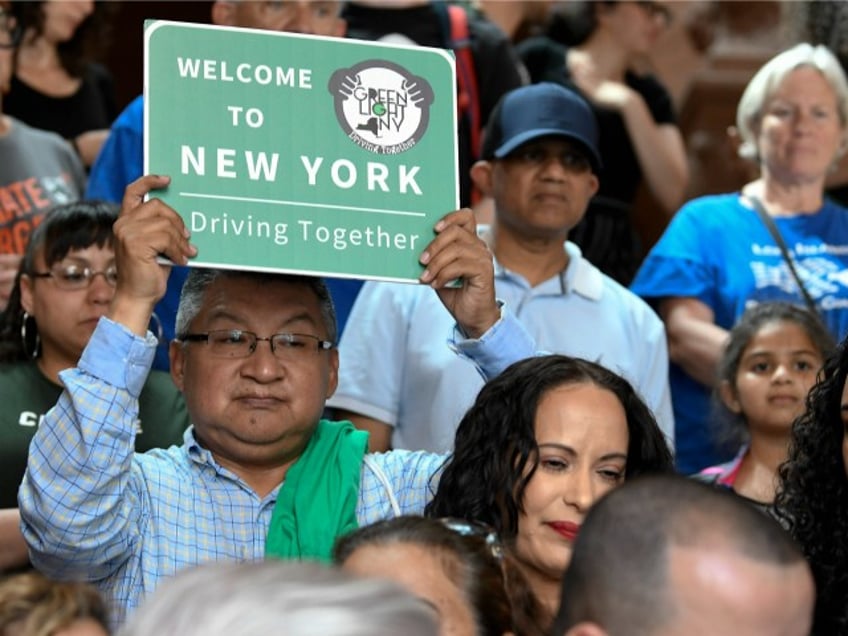 In this June 17, 2019 file photo, a protester holds a sign as members of the state Assembly speak in favor of legislation of the Green Light Bill, granting undocumented immigrant driver's licenses during a rally at the state Capitol, in Albany, N.Y. The bill passed making New York the 13th state to authorize licenses for drivers without legal immigration status. On Monday, Dec. 16 license applicants without a valid Social Security number will be able to apply for a driver's license. An estimated 265,000 immigrants without legal documents are expected to get driver's licenses within three years, more than half of them in New York City, according to the Fiscal Policy Institute.(AP Photo/Hans Pennink, File)